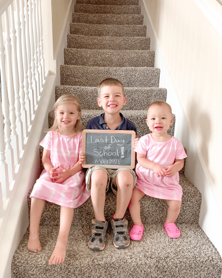 two little girls and a boy posing on the stairs for the first day of school