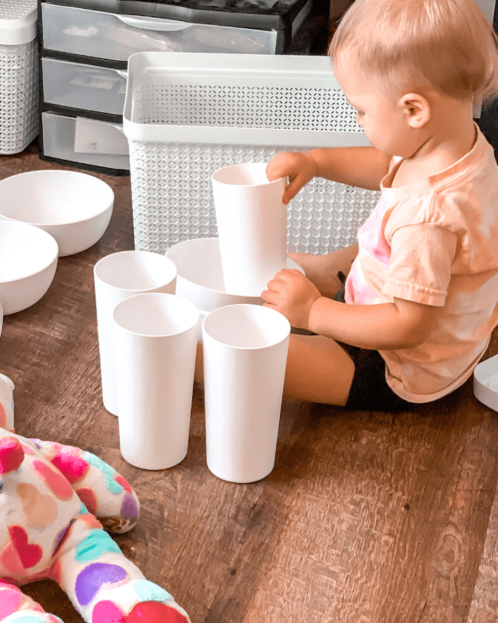 toddler girl playing on the floor with cups